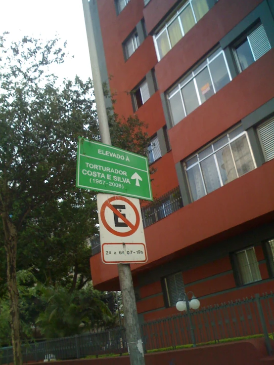 two road signs posted outside of a high rise building