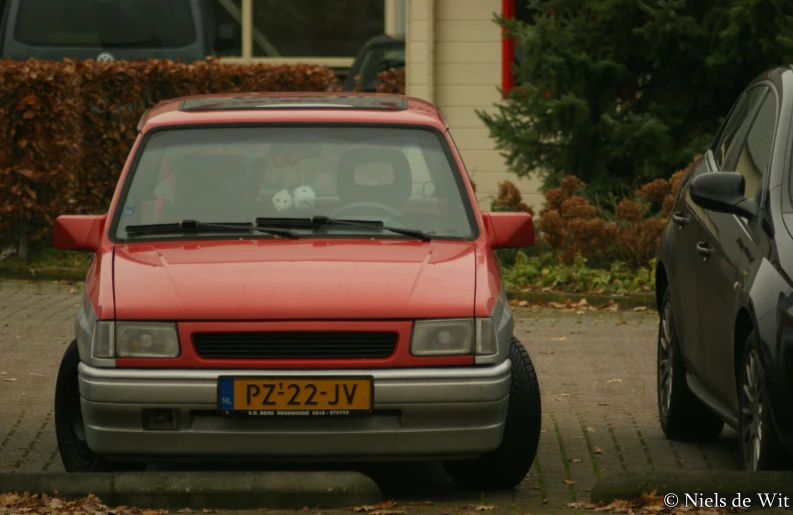 the front of an orange van in a parking lot with another car