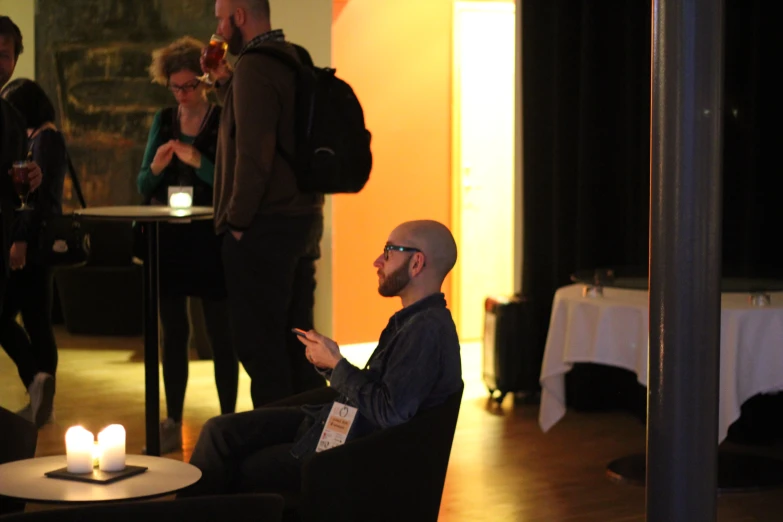 a man with a beard is sitting in a chair next to some people