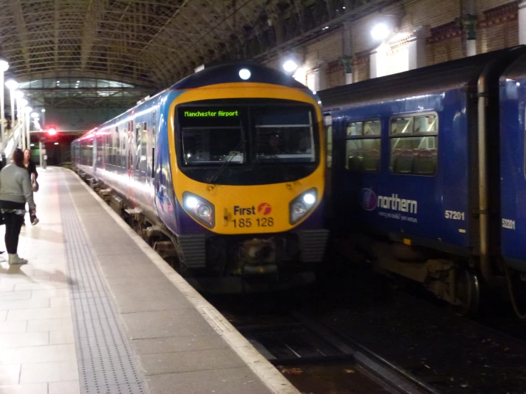 two commuter trains are passing each other in the station