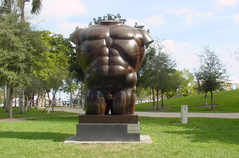 a statue of a mans torso on a green lawn