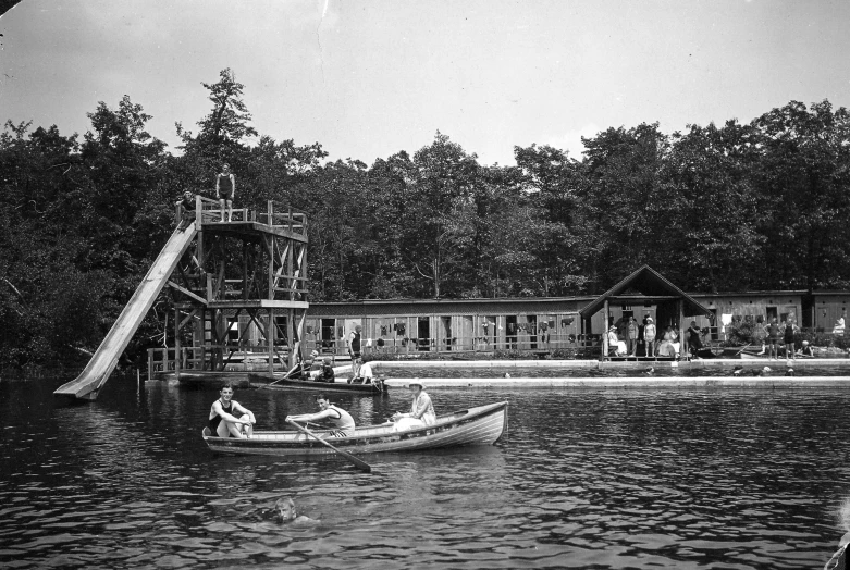 two people are enjoying in a small boat in a lake near a playground area