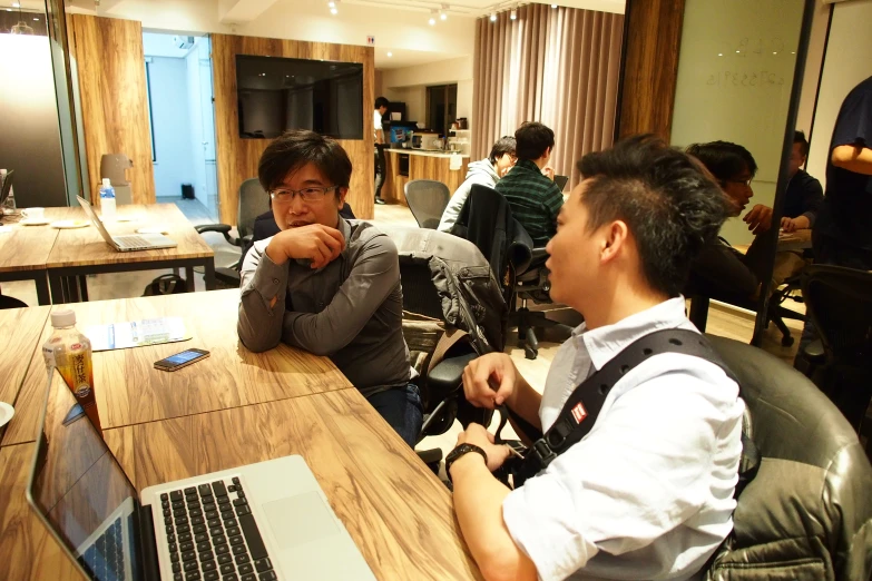 two guys sitting at desks with their laptop computers