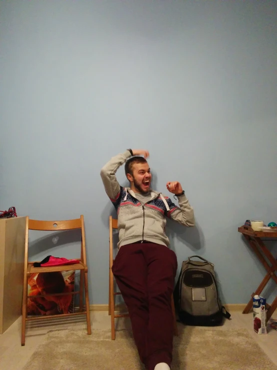 a man wearing a sweater and pants is sitting in a room