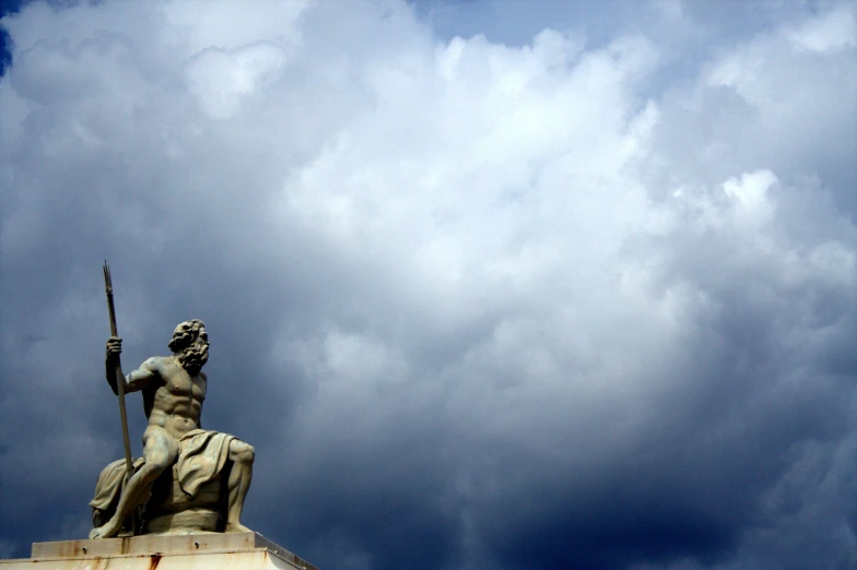 a statue sitting on top of a pedestal holding a spear