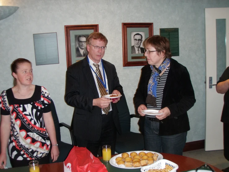 a group of people standing around a table with plates of food on it