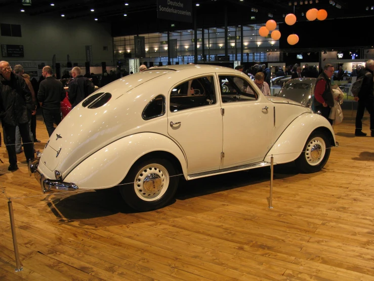 a white vintage beetle sits on display on a hard wood floor