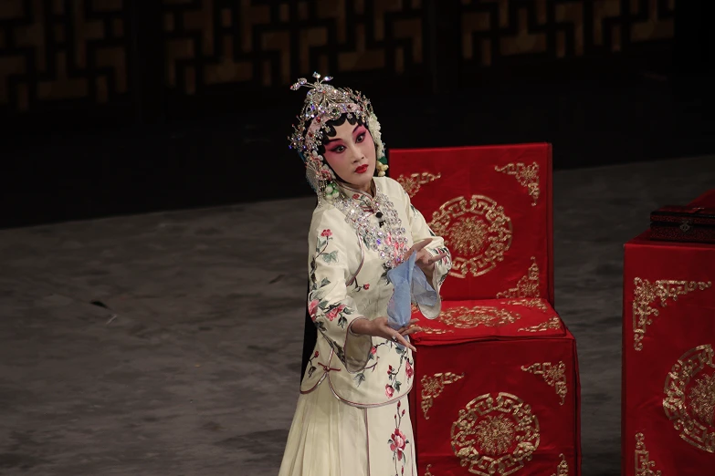 a woman dressed up in oriental attire standing by some red blocks