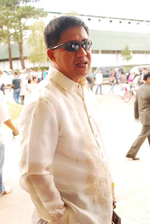 a man in white clothing walking down a street