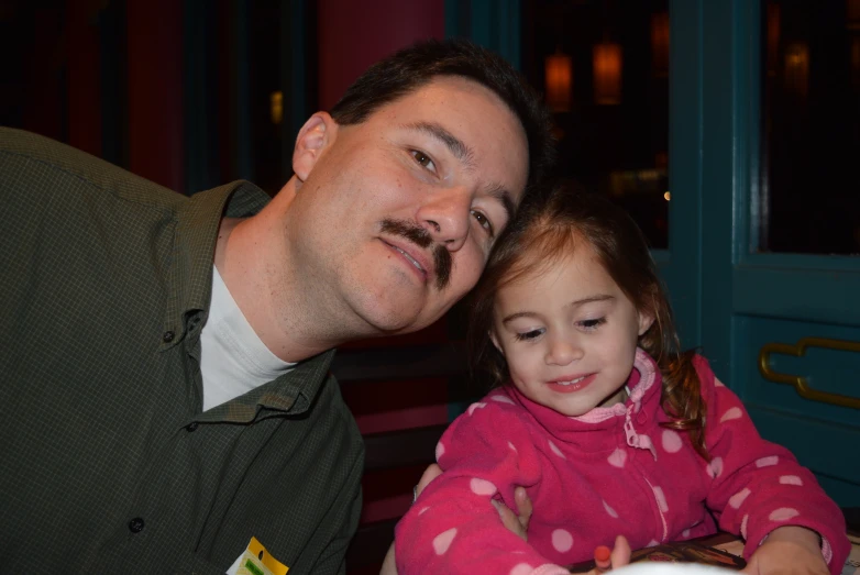 a man is teaching a little girl how to read