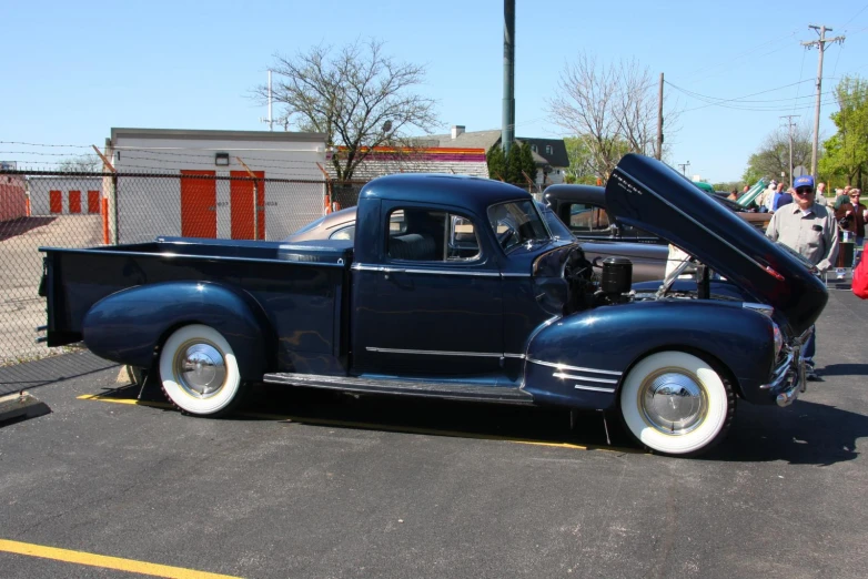 a classic blue pickup truck has a large open trunk