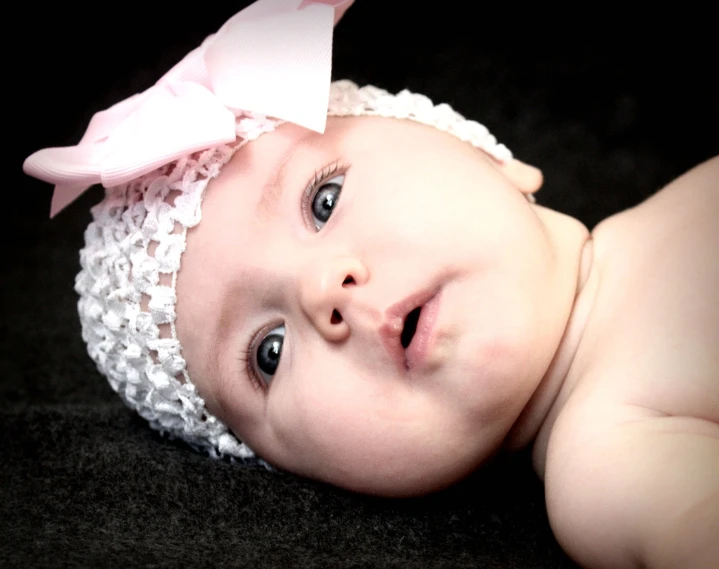 a baby wearing a pink bow on top of it's head