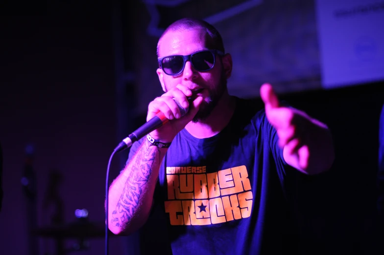 man with sunglasses talking into microphone in dark room