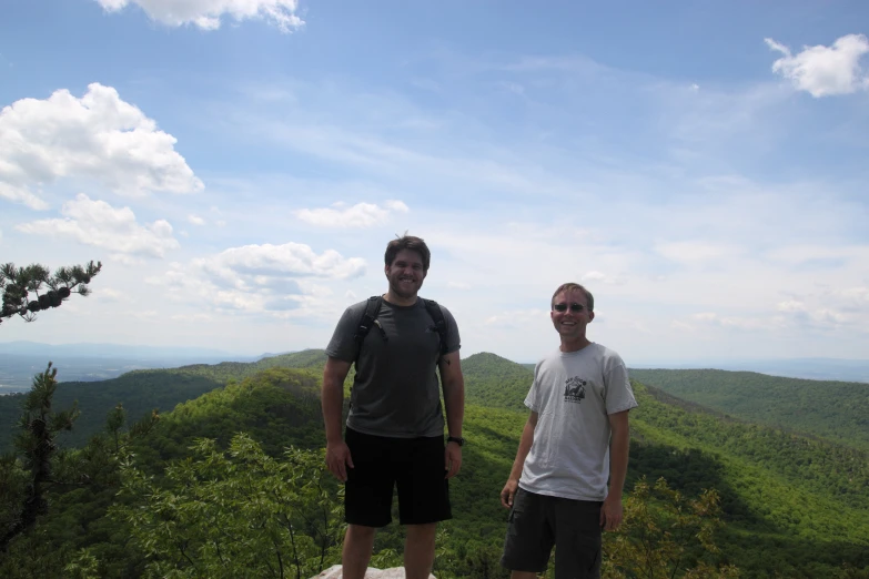 two men pose in front of the mountain side