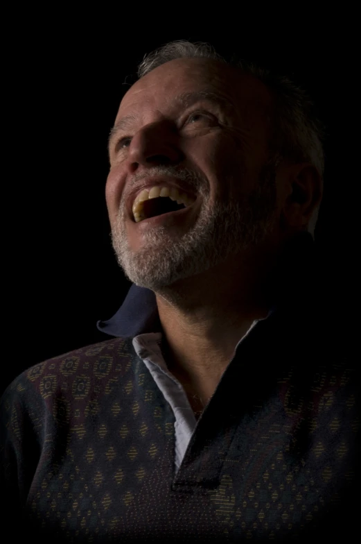 an older man smiles while making a weird face