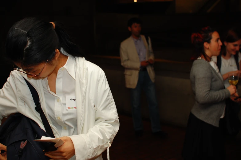 woman standing while others watch her holding her cellphone