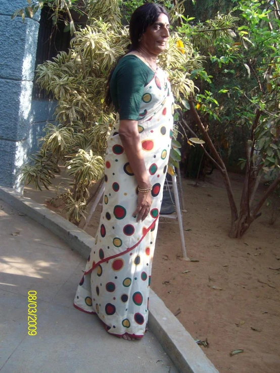 a woman in a colorful saree is standing outside