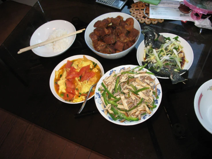 a table topped with bowls of food next to plates