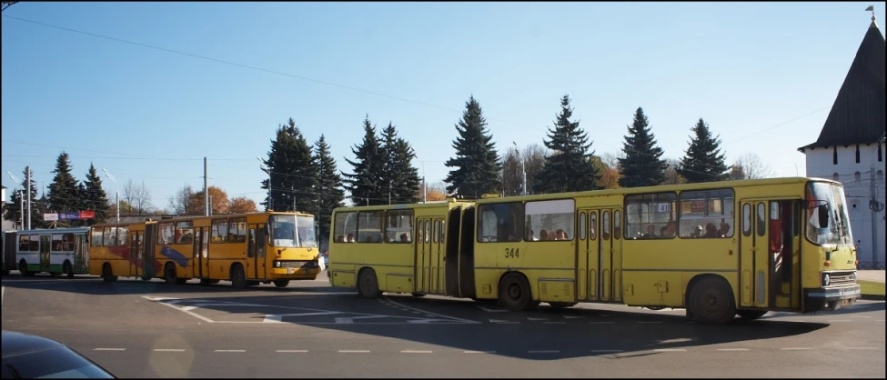 several yellow buses are parked side by side on the street