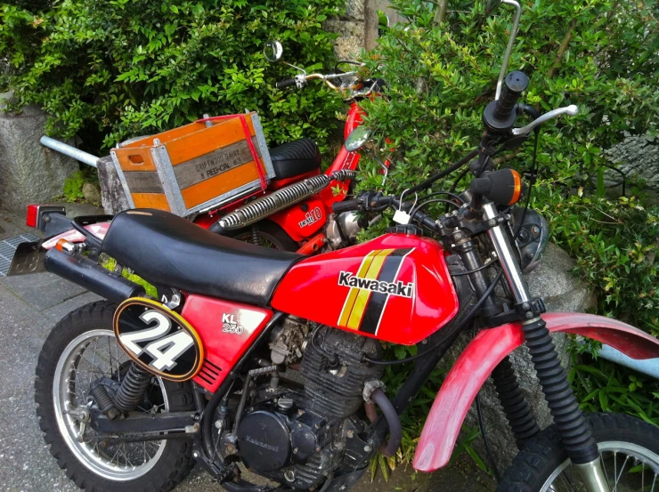 an older honda motorcycle parked beside some shrubbery