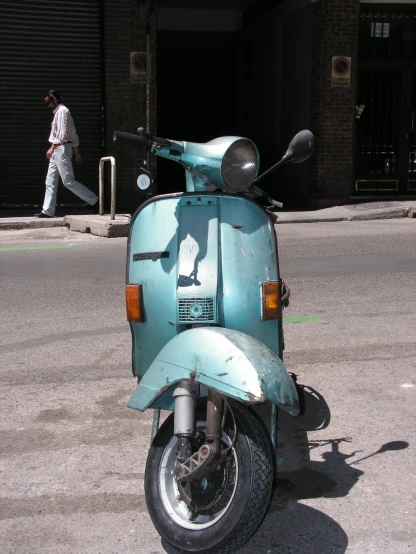 there is a green motor scooter parked in the street