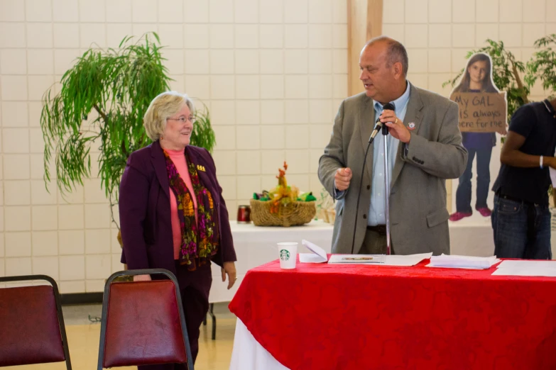 two people are speaking to each other in front of an empty table