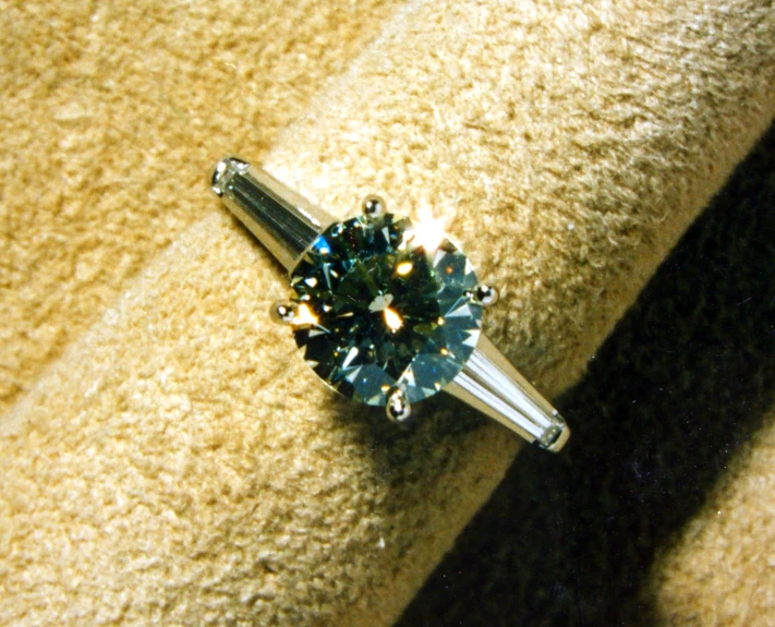 an engagement ring with a fancy diamond setting on a yellow blanket