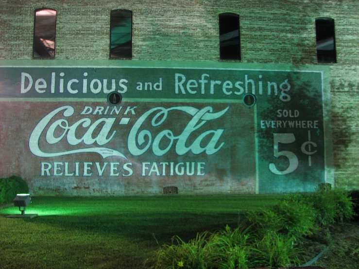 a giant coca cola sign in front of a brick building