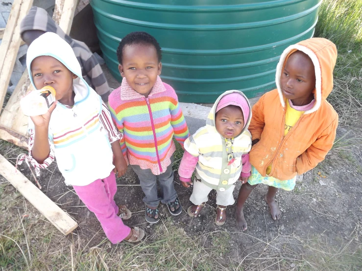 several children standing outside in front of a plastic tank