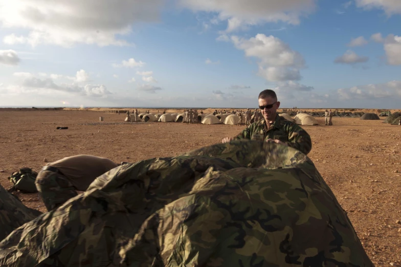 a man in camouflage sitting down with an umbrella in front of him