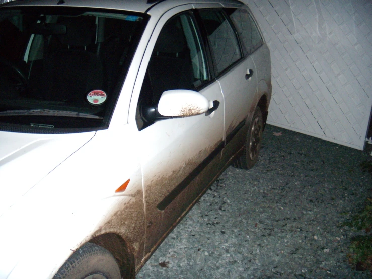 a white car parked in front of a building at night