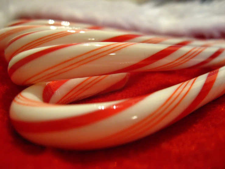 candy canes sitting on red cloth on top of each other