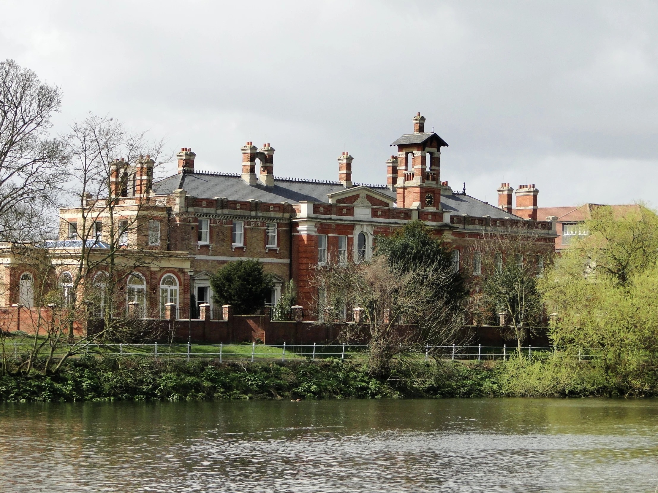 an old mansion near a river with trees and a body of water