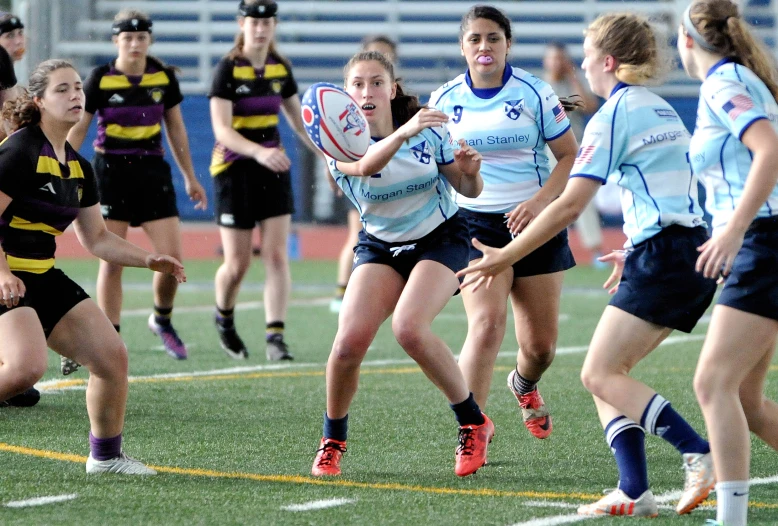 women play rugby in a competition on the field