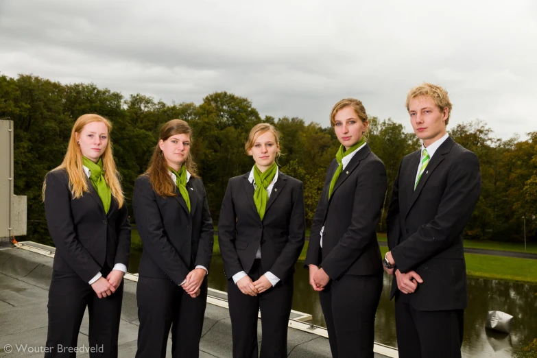 six young business women wearing dark suits and green ties