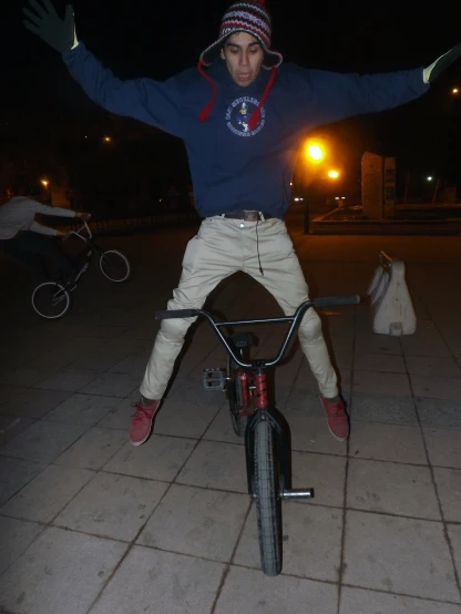 a man is sitting on top of a bike with arms raised