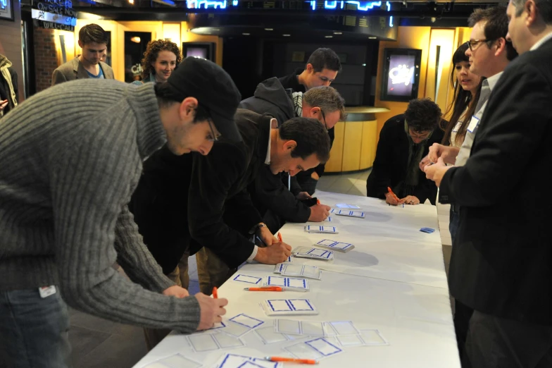 people standing around a table writing on a sheet of paper