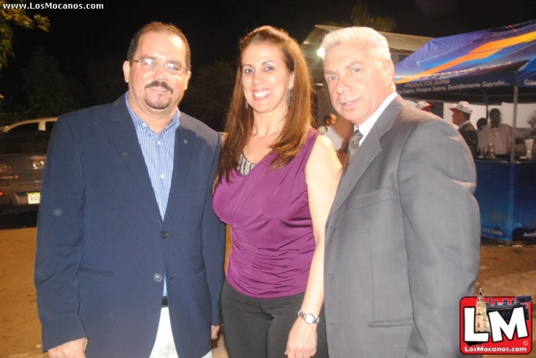 three people standing next to each other near an umbrella