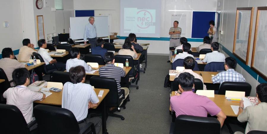 people in a classroom and a man teaching on a whiteboard