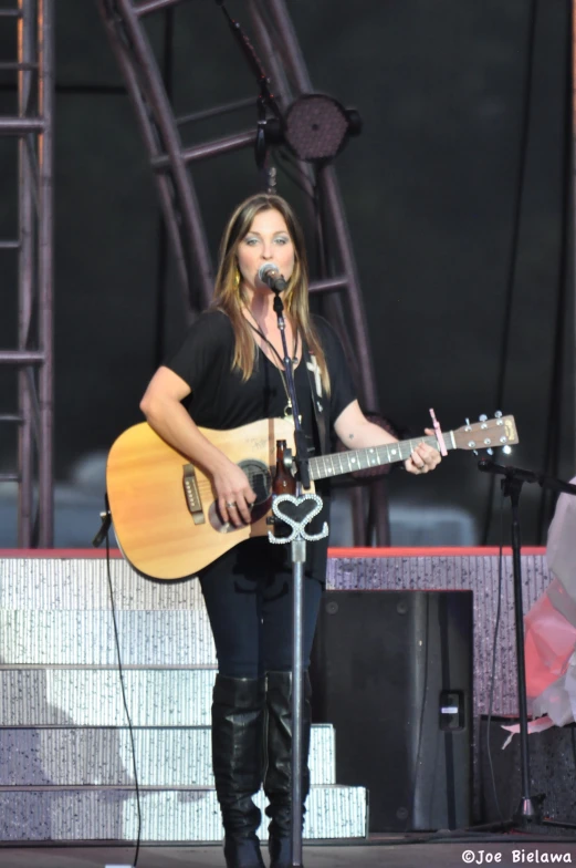 woman standing at the microphone and playing guitar