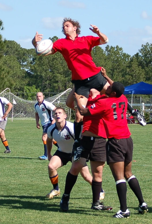 a person leaps to grab a ball as others watch