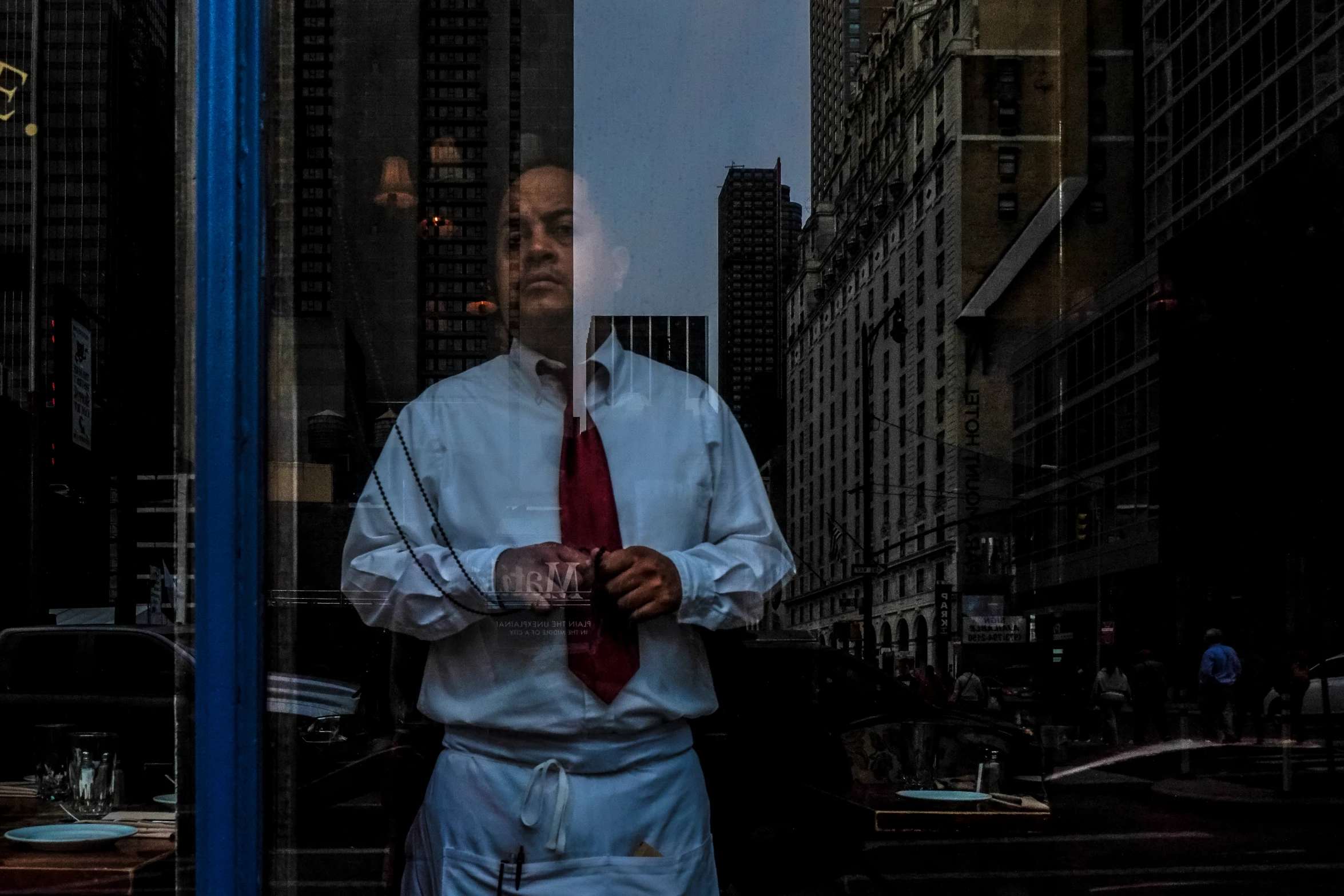 a man in a suit wearing a red tie looking out a window