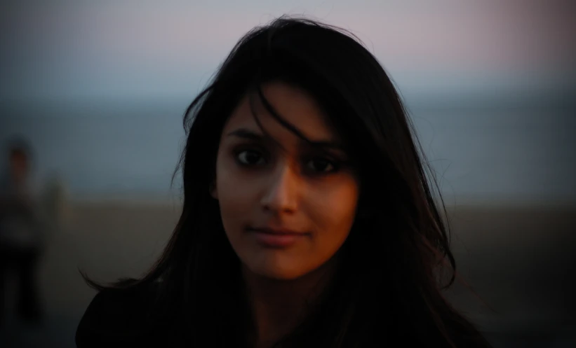 a girl looking into the camera with two people in the background