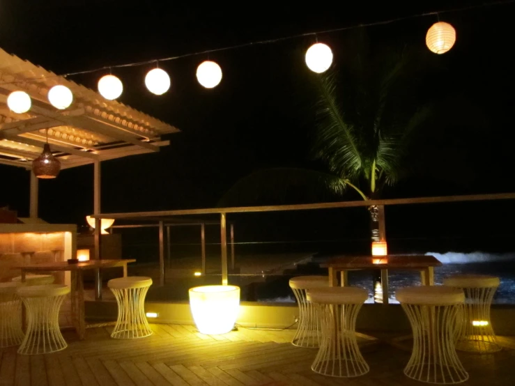 some light on tables on a porch near water