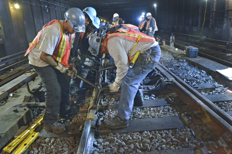 three men working on a railroad track fixing one another