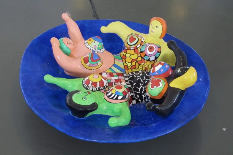 several clay birds on a blue bowl are painted