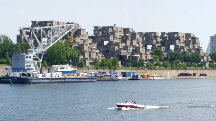 a boat moves past a city with tall buildings on the other side of a river