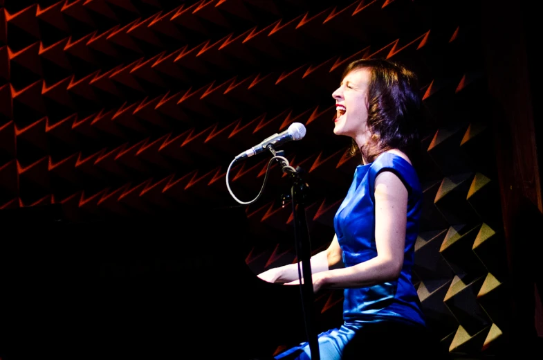 a woman in a blue dress singing into a microphone