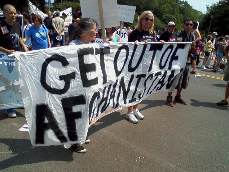 women carrying protest signs while marching down the street