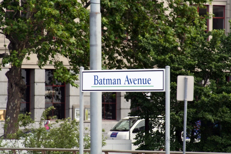 a white sign reading batman avenue on a city street
